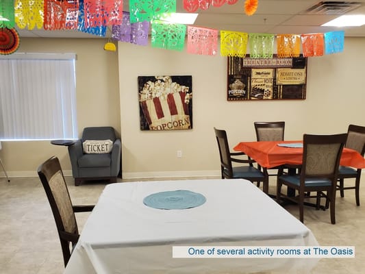 Brightly decorated activity room with tables and chairs at The Oasis.