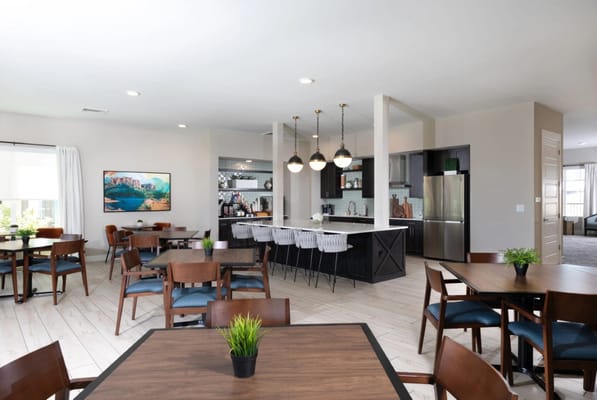 A spacious dining area with wooden tables and a modern kitchen
