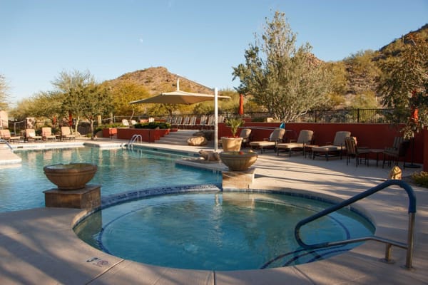 Pool area with a hot tub and lounge chairs at Solera at Johnson Ranch
