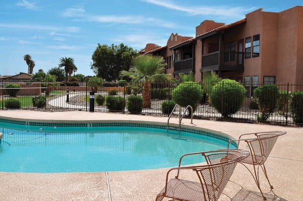 Pool area with lounge chairs and surrounding greenery at Emerald Springs Senior Living
