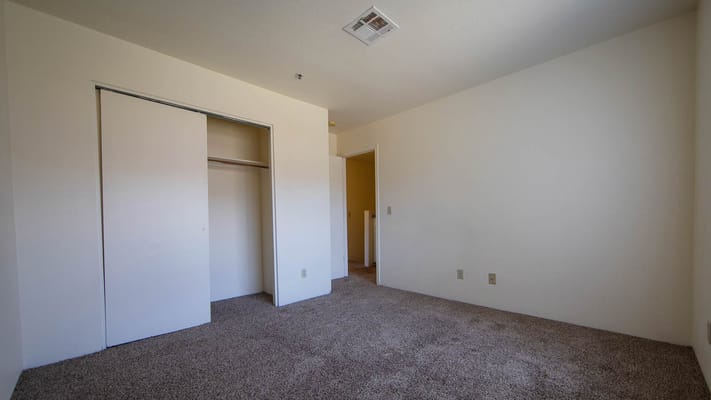 An empty room with beige walls and carpeted flooring.