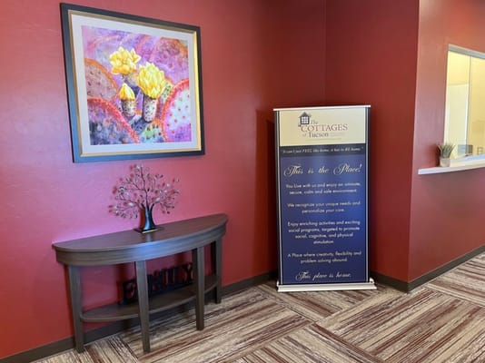 Lobby area with artwork and informational banner at The Cottages of Tucson.