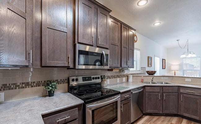 A modern kitchen with dark wood cabinets and stainless steel appliances.