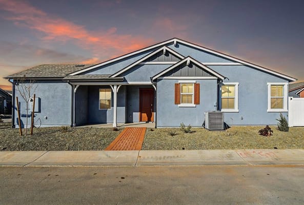 Exterior of a blue apartment building with a landscaped front yard.