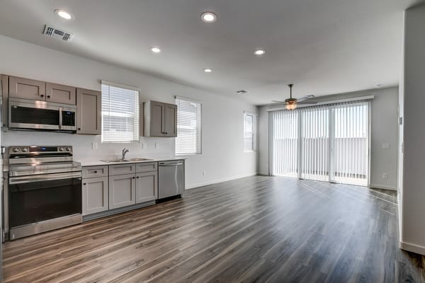 Modern kitchen and living space with wooden flooring and large windows.