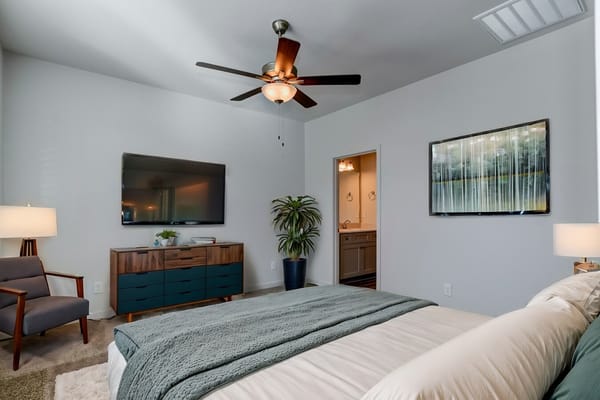 A stylish bedroom featuring a TV, dresser, and a comfortable bed.