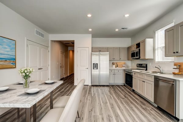 A contemporary kitchen with a dining table and stainless steel appliances.