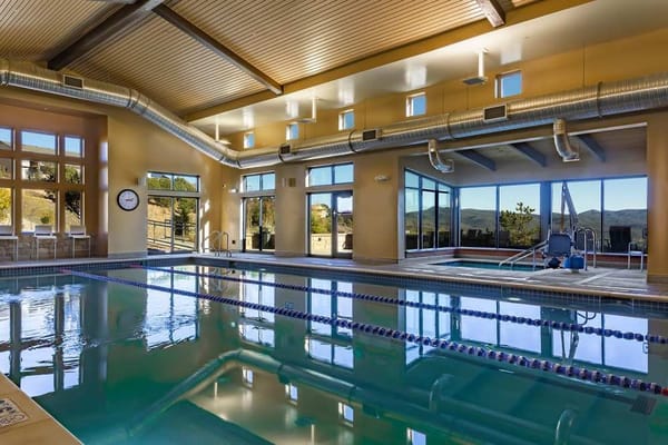 Indoor swimming pool with large windows and mountain views