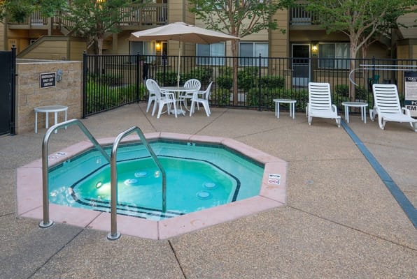 Outdoor pool with seating and umbrellas near the apartments