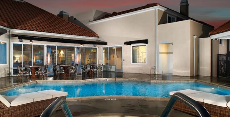Swimming pool area with seating at Villa Anaheim Senior Apartments