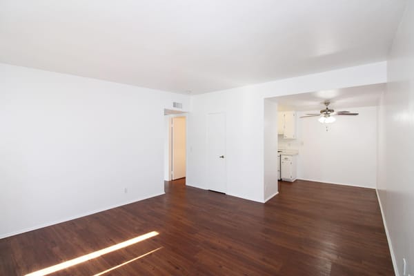 Bright, empty apartment living room with a kitchen area
