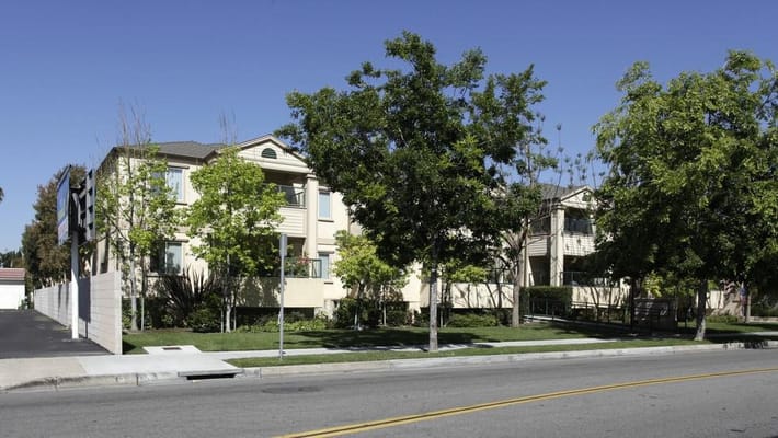 Front view of the Sterling Court Senior Apartments surrounded by greenery.