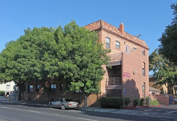 Outside view of Delta Plaza Apartments showing the brick building and surrounding trees.