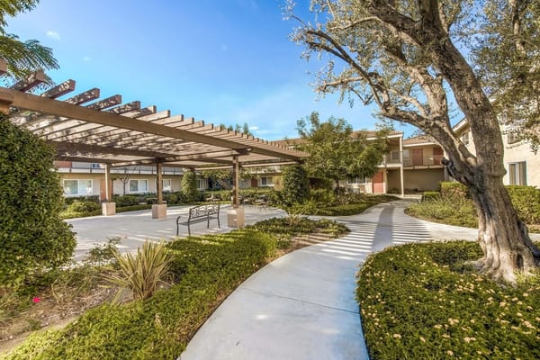 Lush garden path with pergola at Santiago Villas Senior Apartments