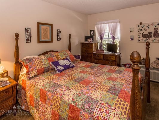 A brightly decorated bedroom with a quilted bedspread and wooden furniture.