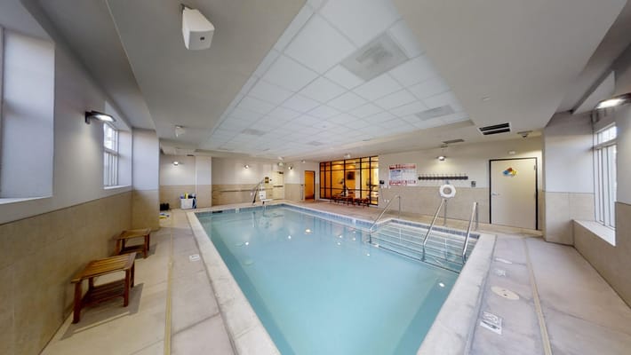 Indoor pool area with chairs and lounge space