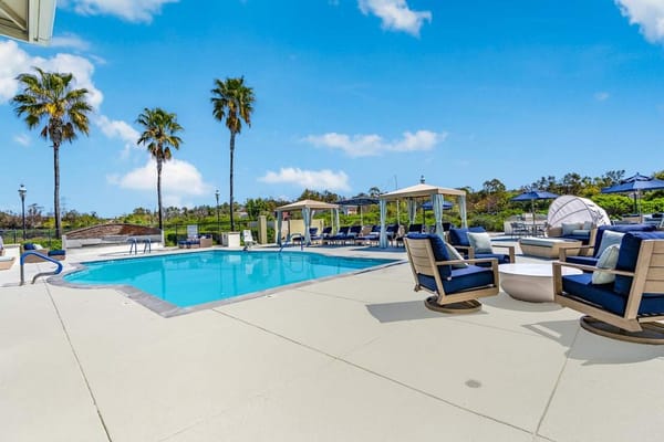 Outdoor pool area with lounge chairs and palm trees