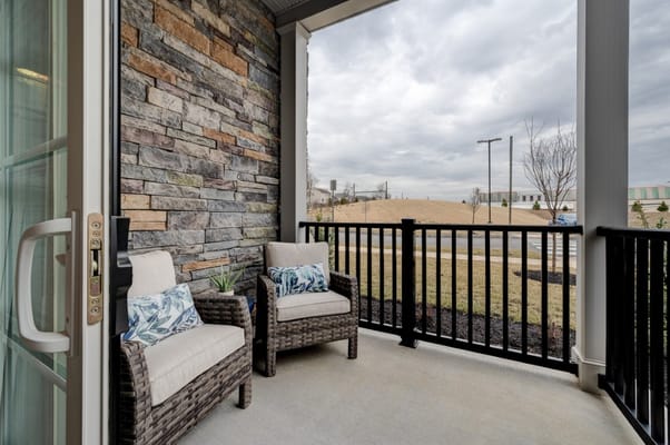 Cozy balcony with two chairs and stone wall backdrop