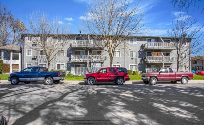 Front view of La Loma Senior Apartments with parked vehicles