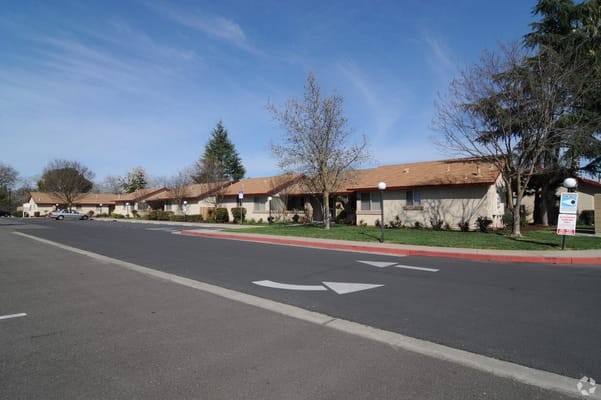 Exterior of Sherwood Manor Senior Apartments with parking lot and trees.