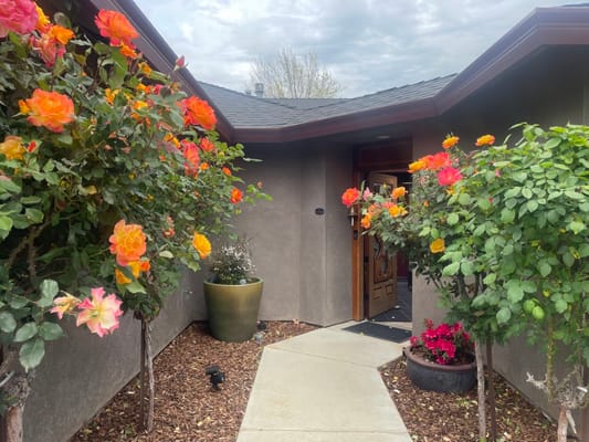 Entrance of a senior living facility surrounded by blooming flowers