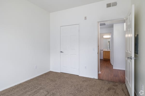 Empty resident room with beige carpet and white walls