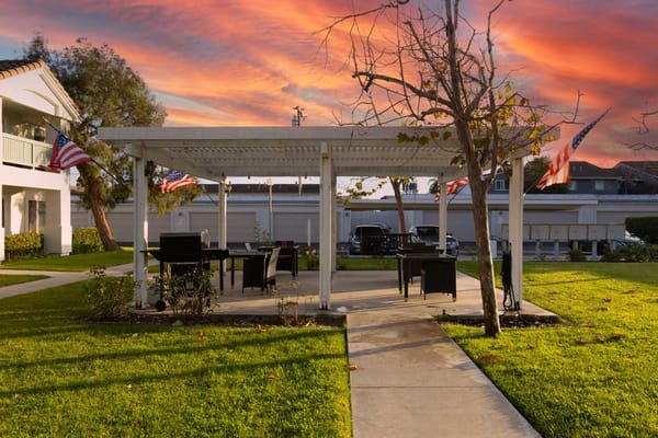 Outdoor seating area with a pergola and flags during sunset