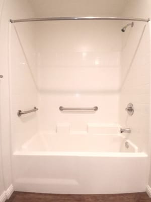 A spacious accessible bathroom with grab bars and a bathtub.
