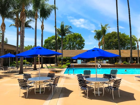Outdoor pool area with blue umbrellas and seating at Huntington Landmark