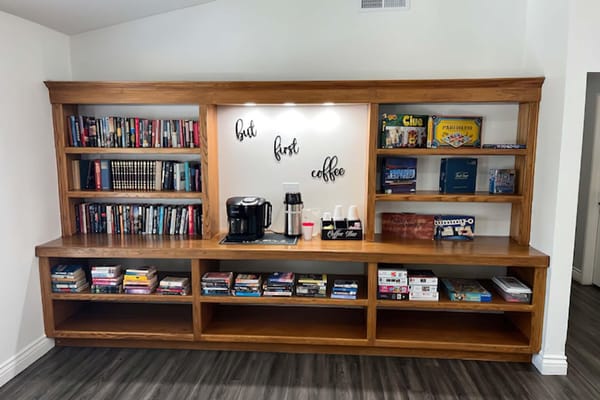Coffee station next to a bookshelf filled with books and games.