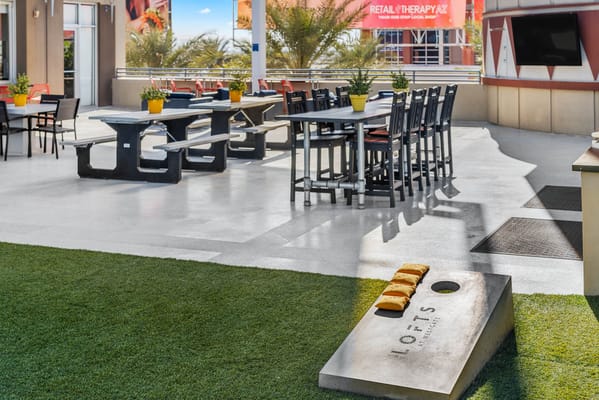Outdoor seating area with tables and cornhole game