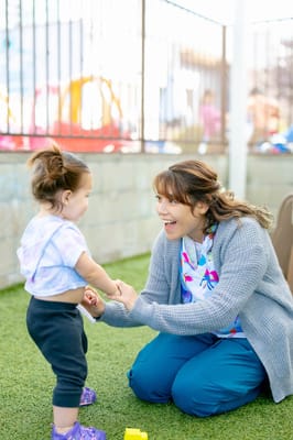 A caregiver interacting with a child in an outdoor space
