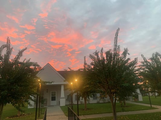 Sunset view over Glen East Senior Apartments with vibrant skies and trees.