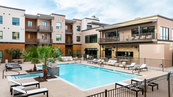 Outdoor pool area with seating and apartments