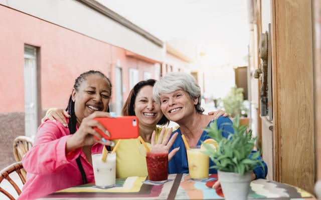 Three women enjoying drinks and taking a selfie outdoors