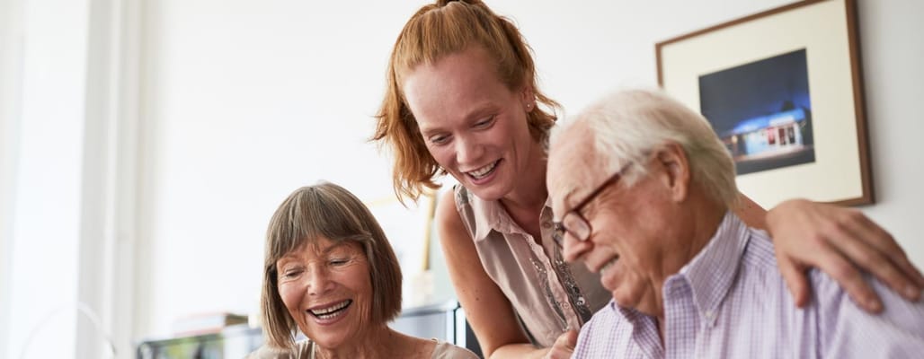 Staff interacting with smiling residents in a bright interior