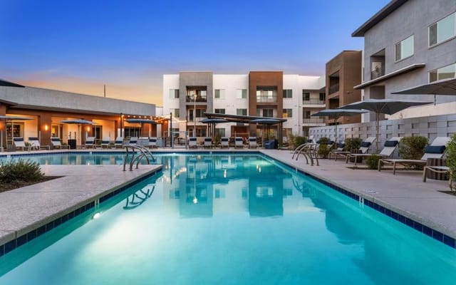 Outdoor swimming pool with lounge chairs and buildings in background