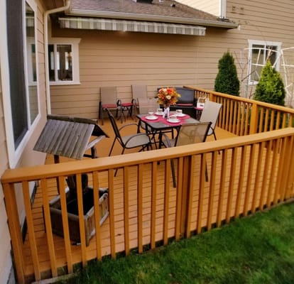 A cozy outdoor patio with a table set for tea and four chairs.