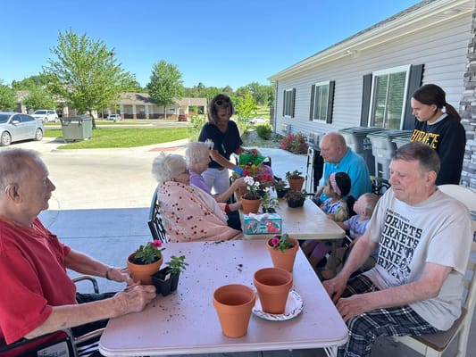 Seniors at Sunflower Care Homes engaging in a plant potting activity outdoors.