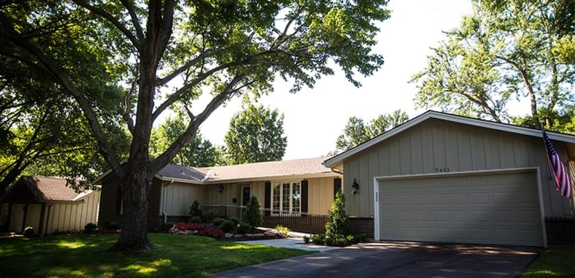 Front view of SeniorCare Homes with landscaping and large tree