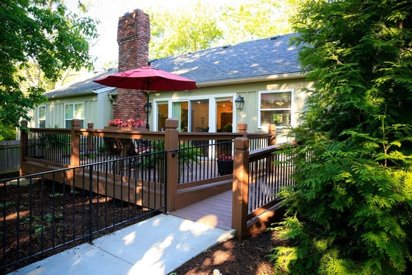A patio with a red umbrella and landscaped garden at SeniorCare Homes.