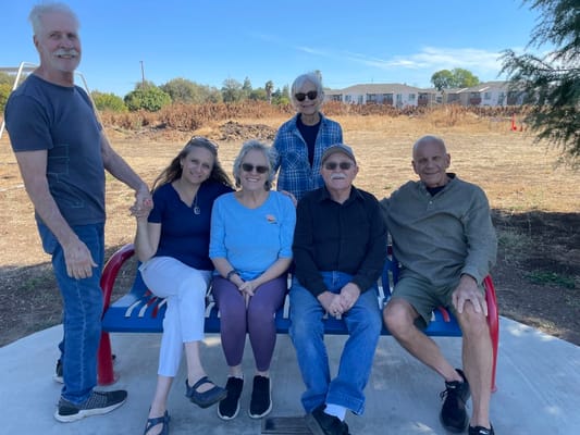 Residents and staff sitting together on a bench outside