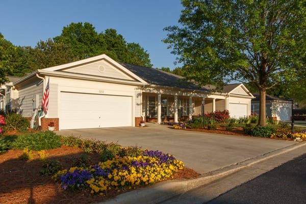 Exterior view of Magnolia Trace facility with flowerbeds and a garage
