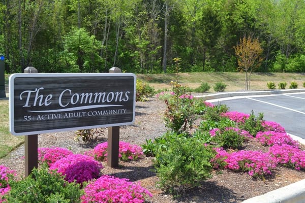 Sign of 'The Commons - 55+ Active Adult Community' with flowers
