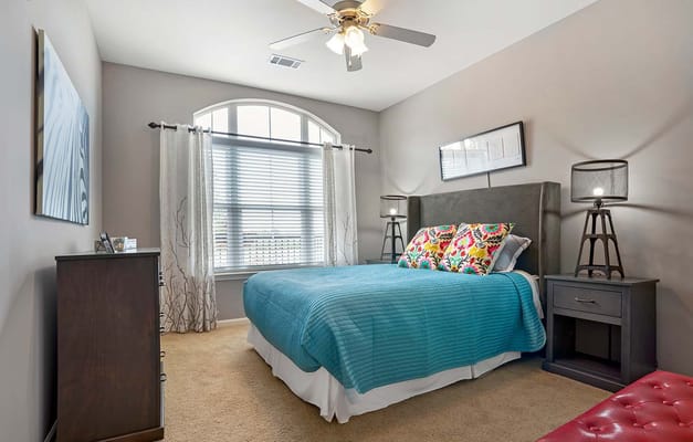 Stylish bedroom featuring a blue quilt and colorful pillows.