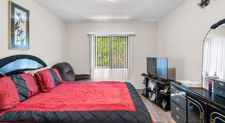 A well-furnished bedroom with a red bedspread and a TV.