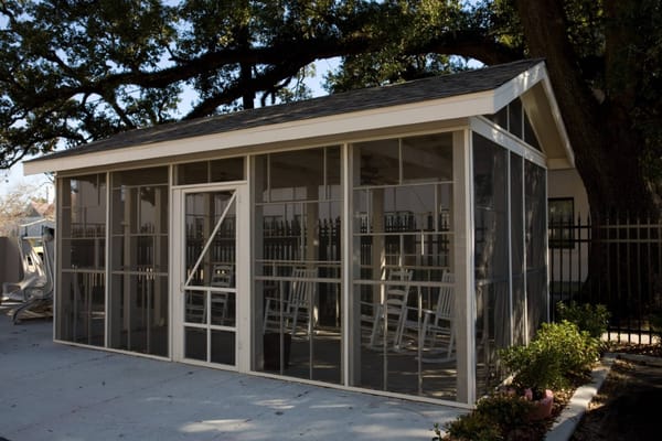 A screened patio with rocking chairs at Baptist Oaks Apartments.