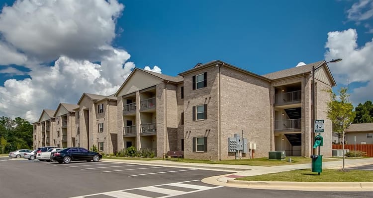 View of the exterior of Somerville Apartments with parking area