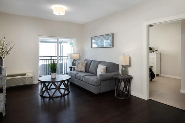 Spacious living room with a couch, round table, and balcony access