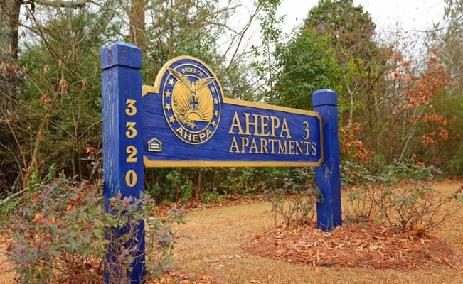 Sign for Ahepa 3 Senior Apartments in a garden setting